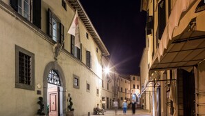A narrow street with buildings on either side, a flag, and a bench. - Palazzo Leopoldo Dimora Storica & Spa (Radda in Chianti)