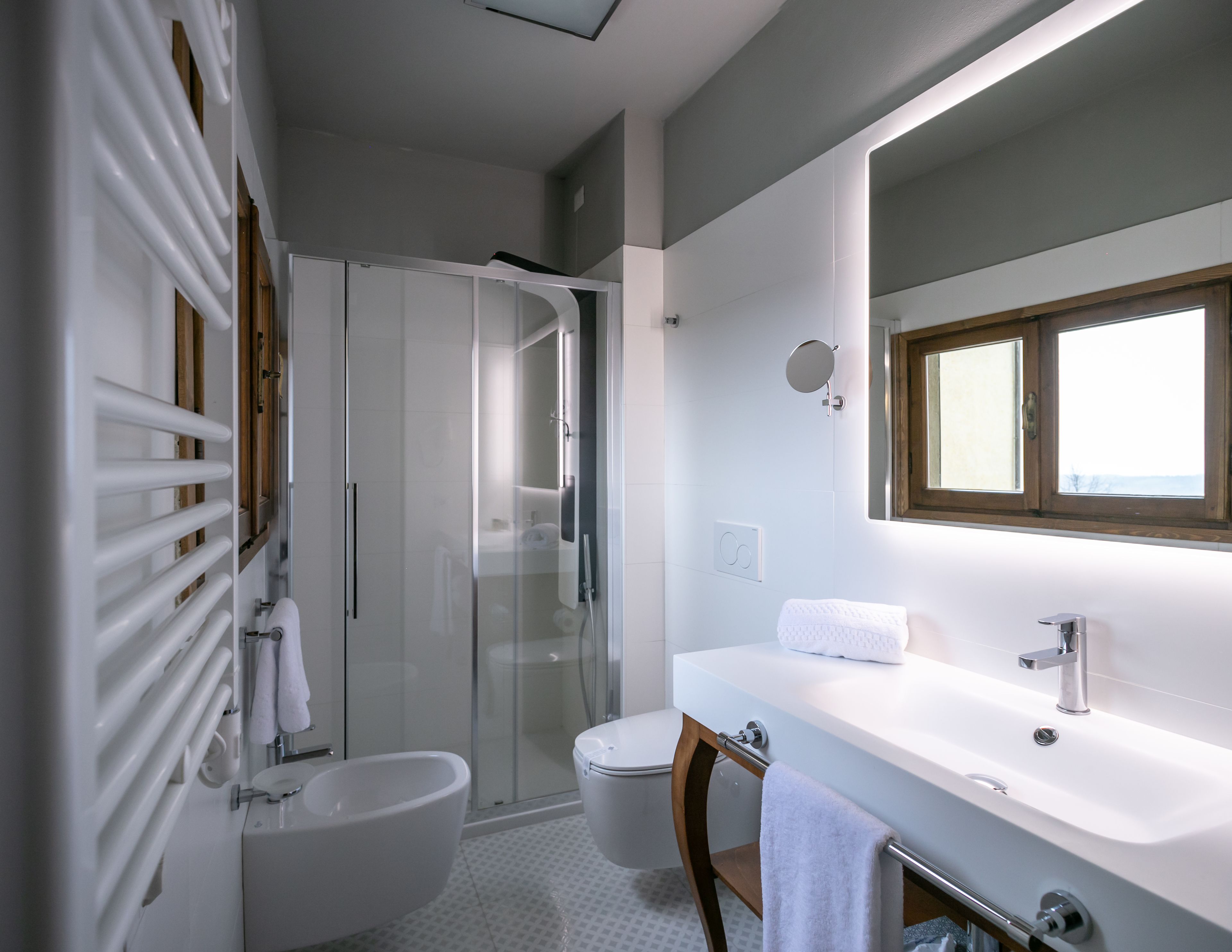 A modern bathroom with a glass-enclosed shower, a white sink, and a large mirror.