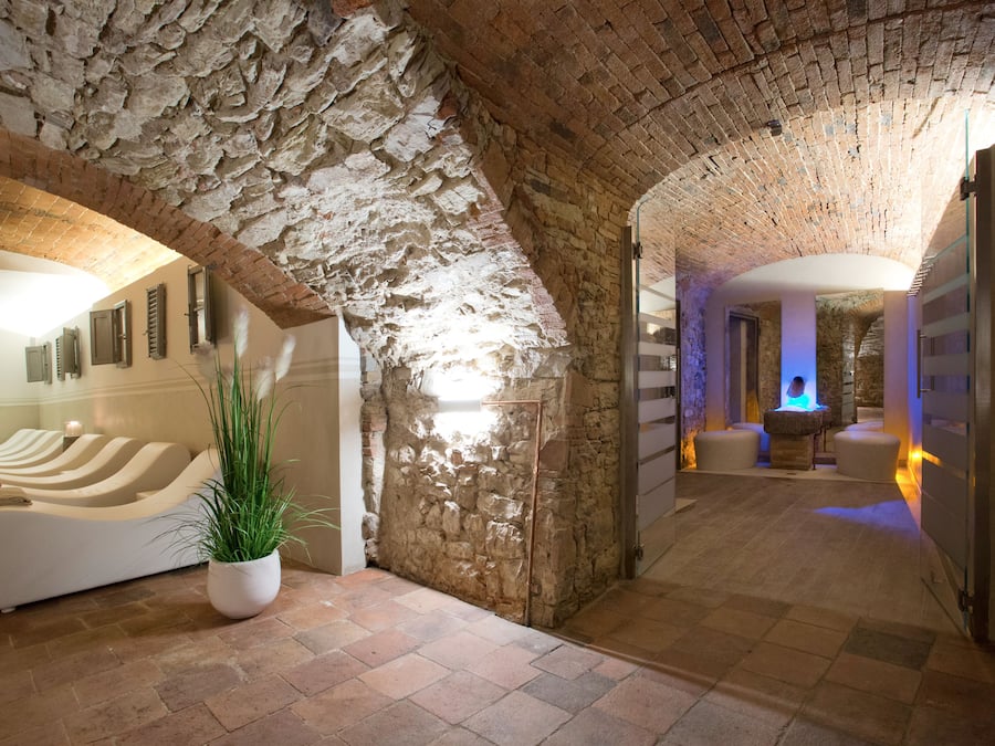 A spa area with stone walls, a white massage chair, and a potted plant.