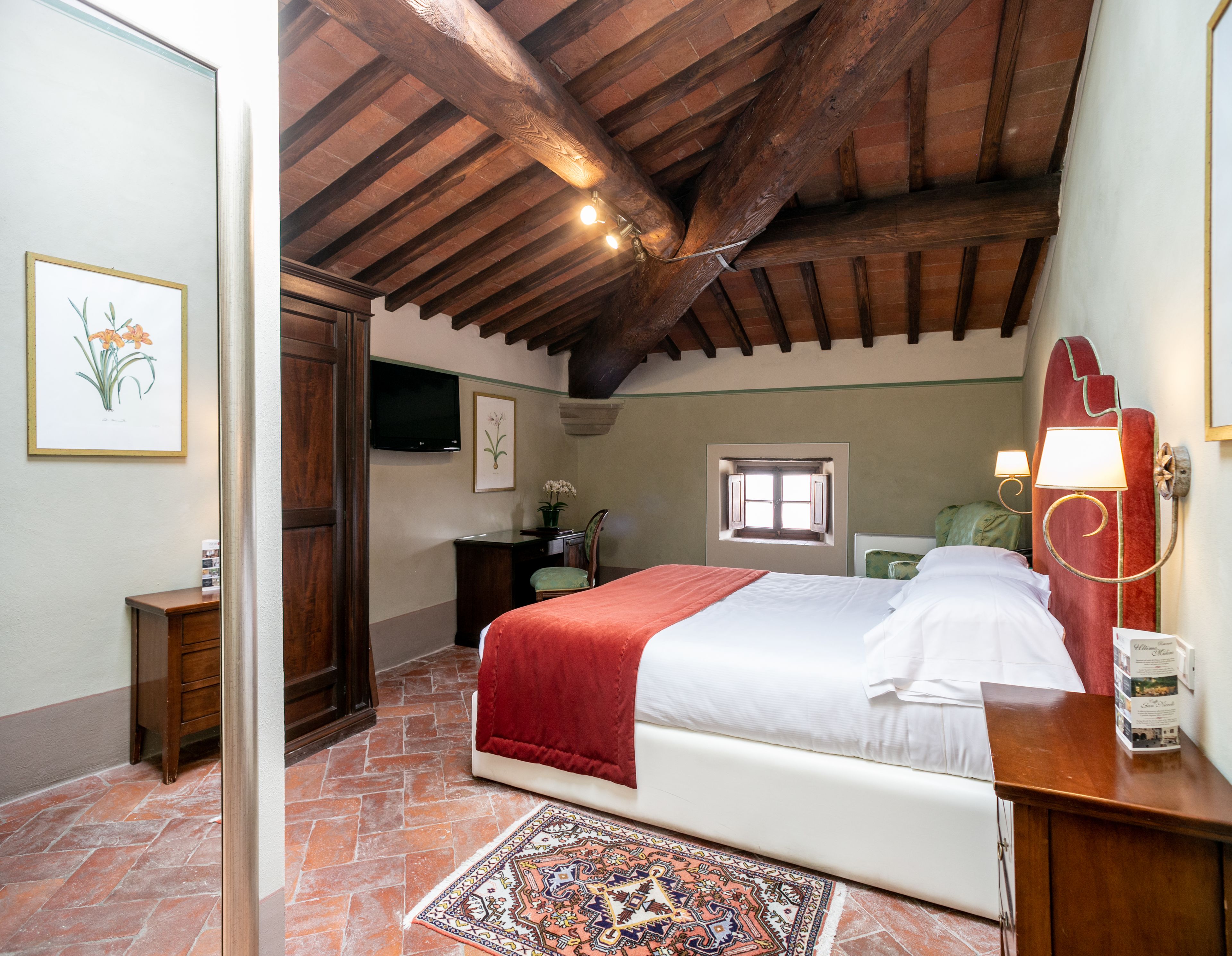 Une chambre à coucher avec un lit, un bureau, une chaise, une fenêtre et un téléviseur fixé au mur.