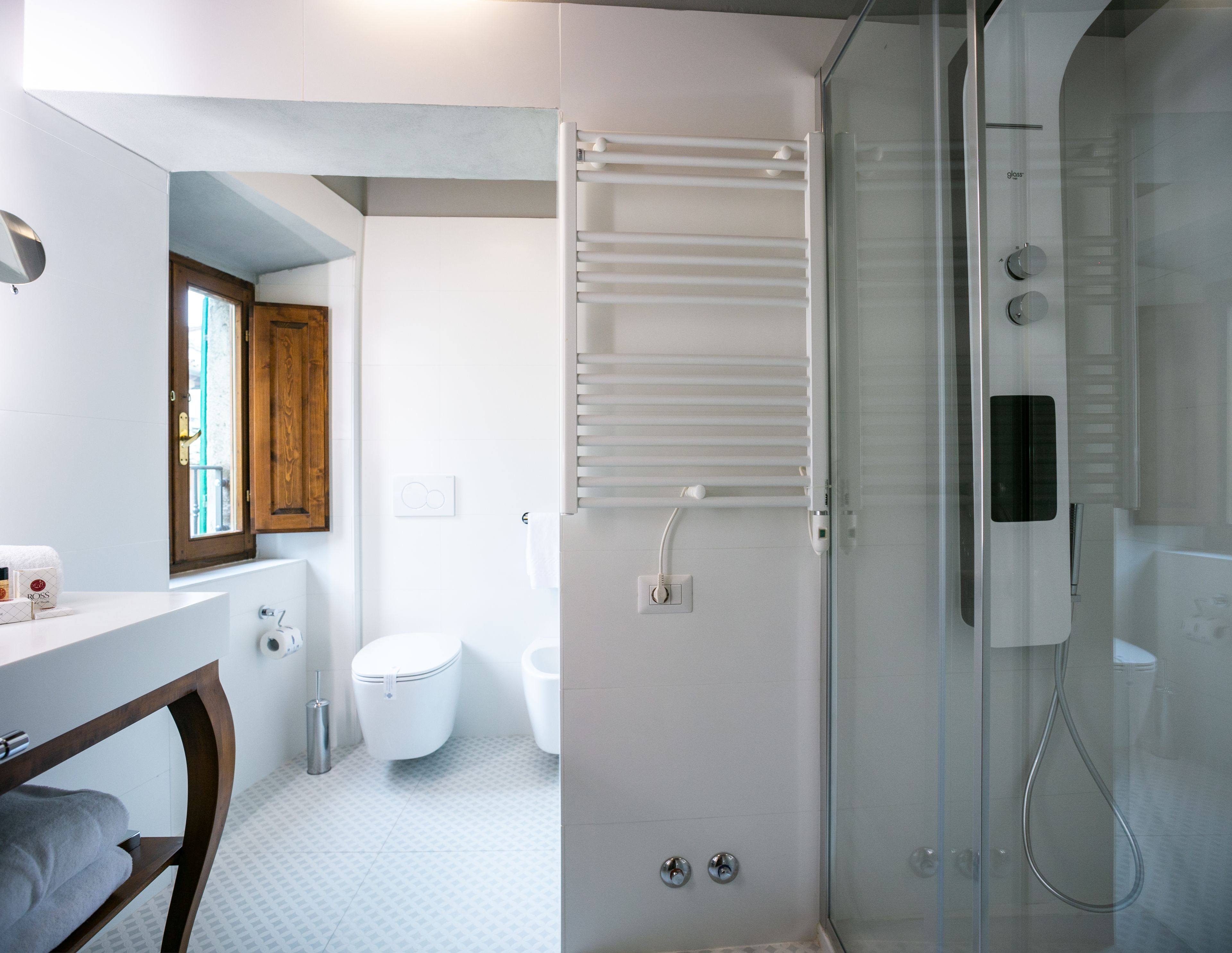 Ein modernes Badezimmer mit Duschkabine aus Glas, einer weißen Toilette, einem Holzschrank und einem Handtuchhalter.