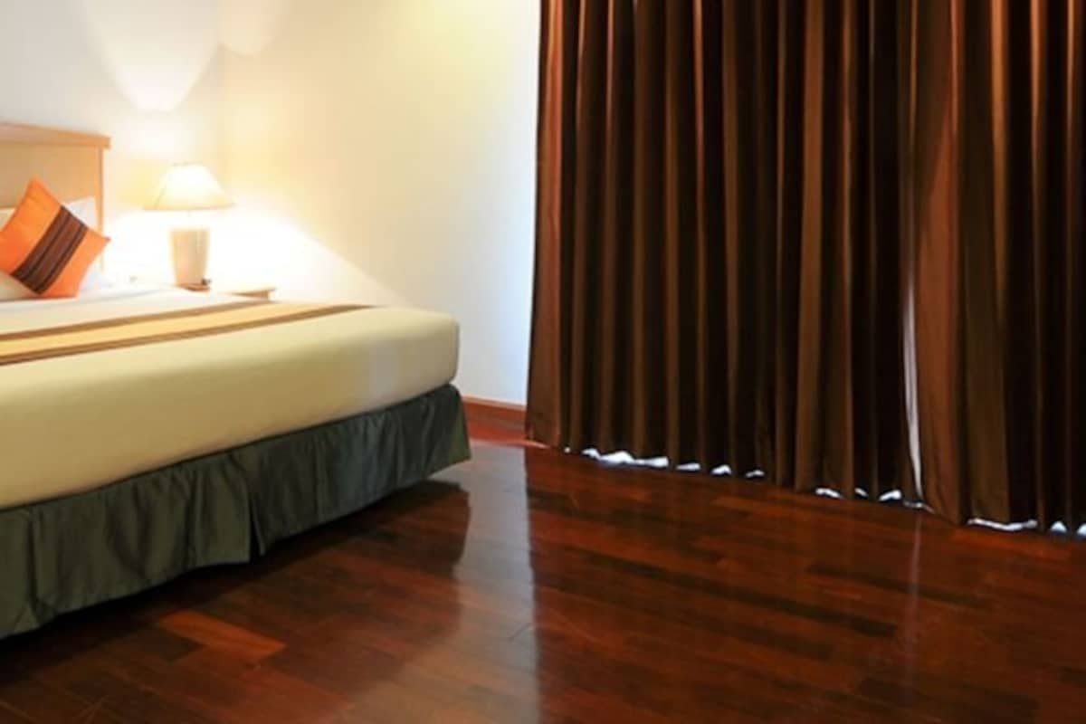 Una habitación de hotel con cama, mesita de noche, lámpara y cortina.