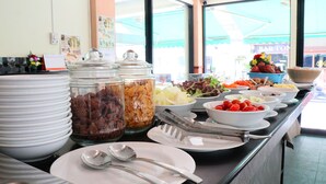 Una mesa de buffet con distintos alimentos y utensilios.
