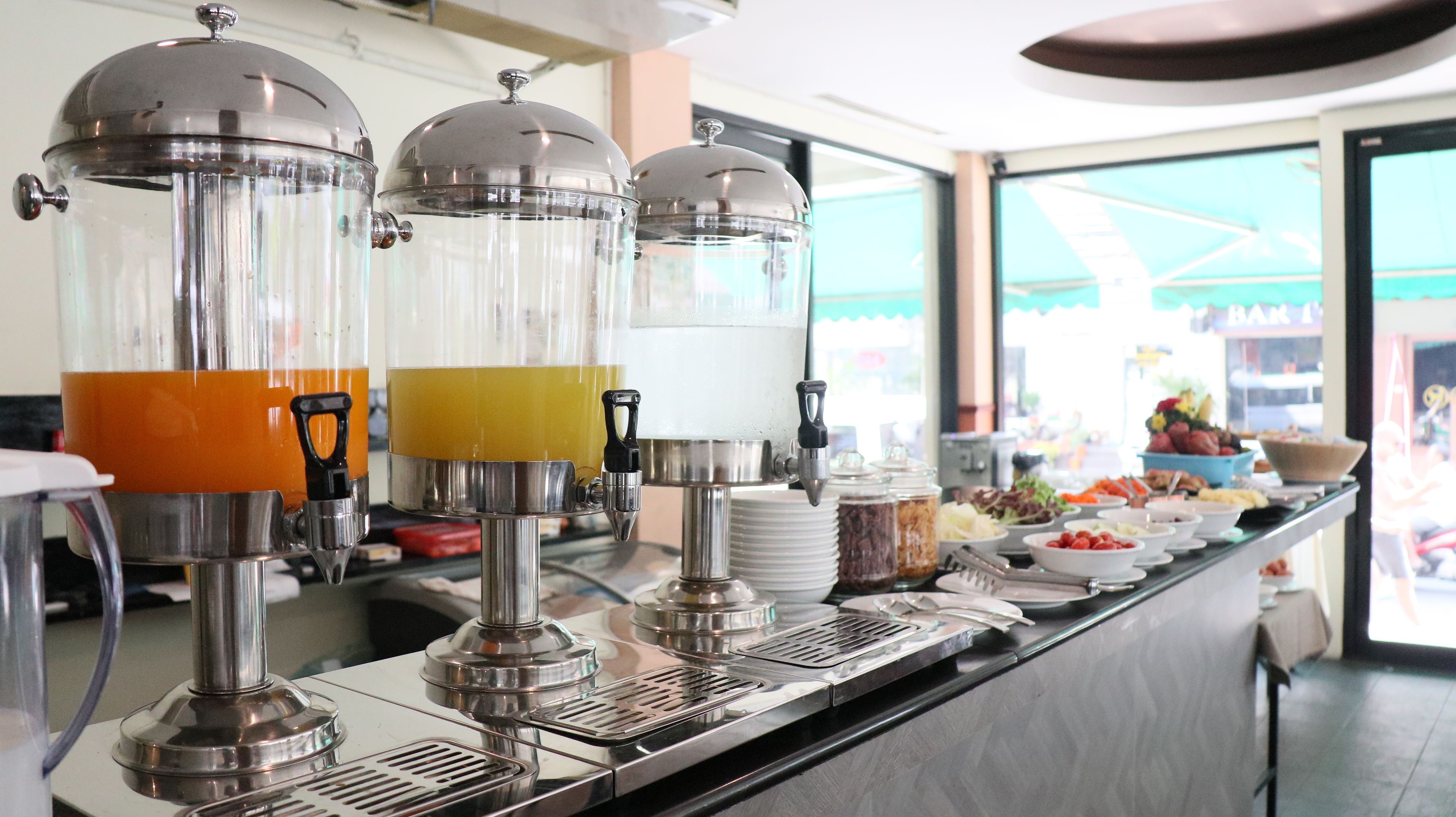 A buffet setup with multiple beverage dispensers and a variety of food items.