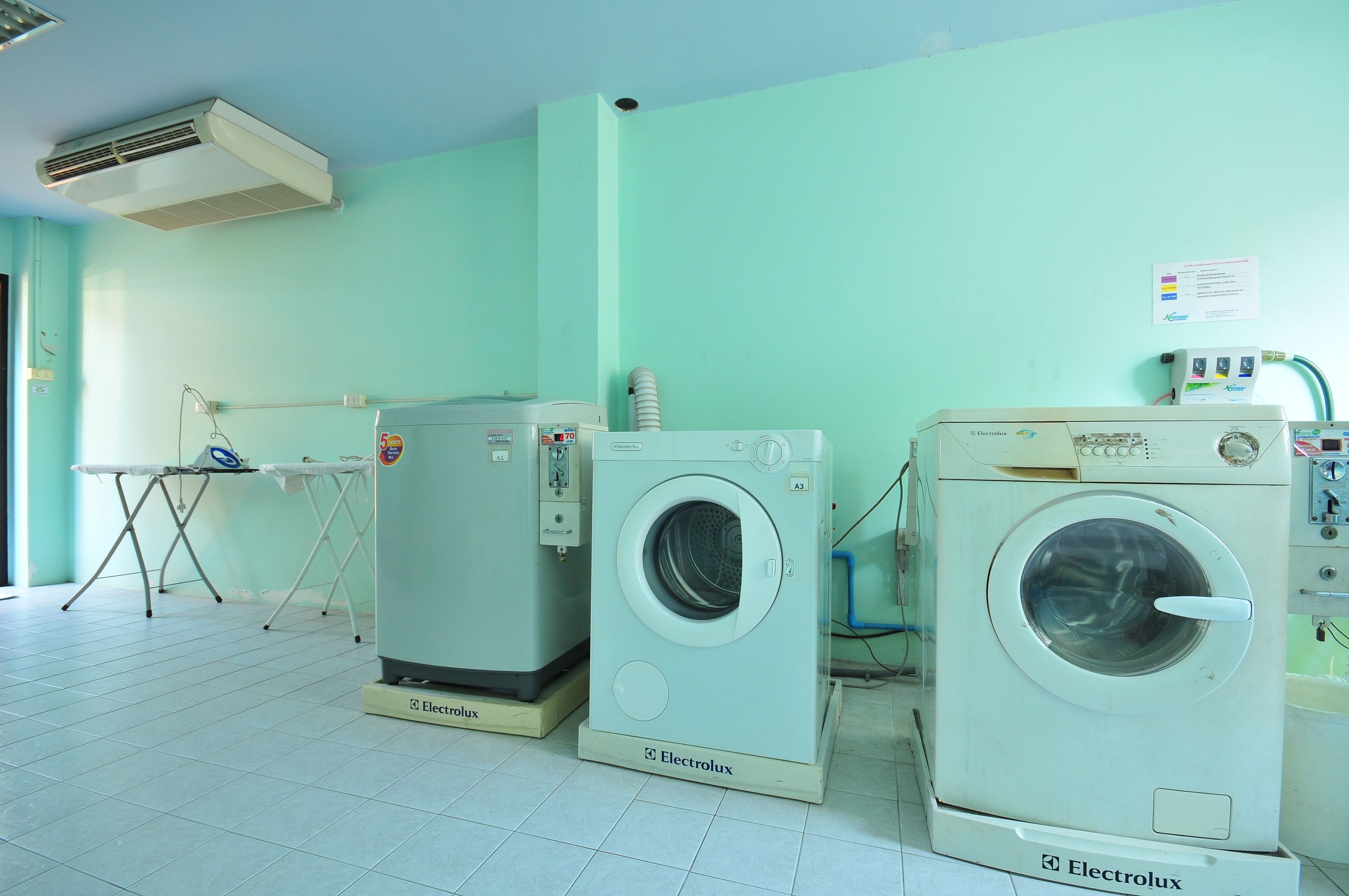 Une buanderie équipée de deux machines à laver Electrolux, d’un sèche-linge et d’une table à repasser.