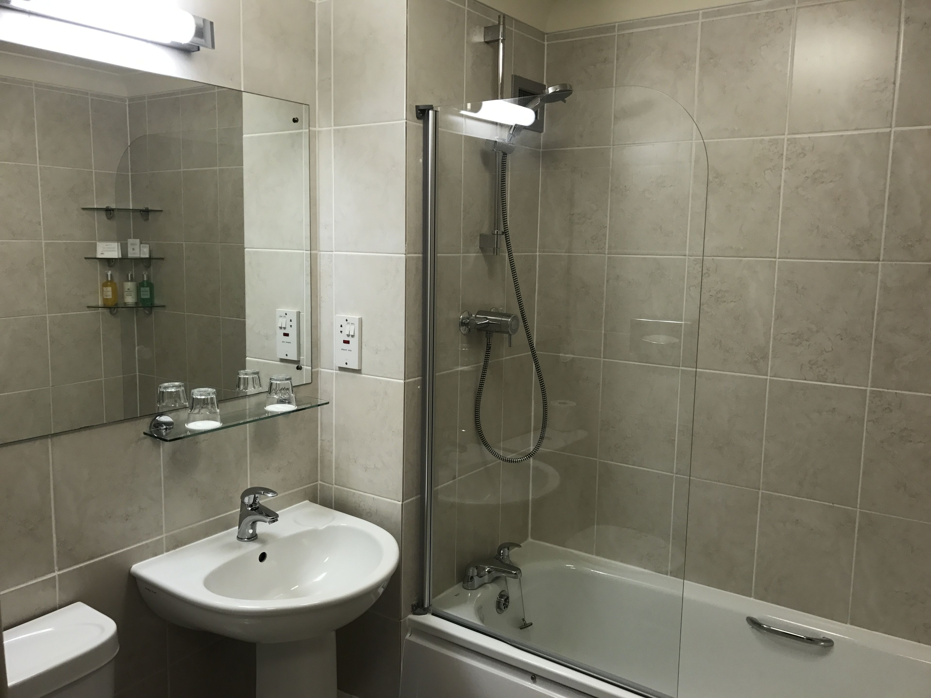 A modern bathroom with a glass-enclosed shower, a white sink, and a mirror above the sink.