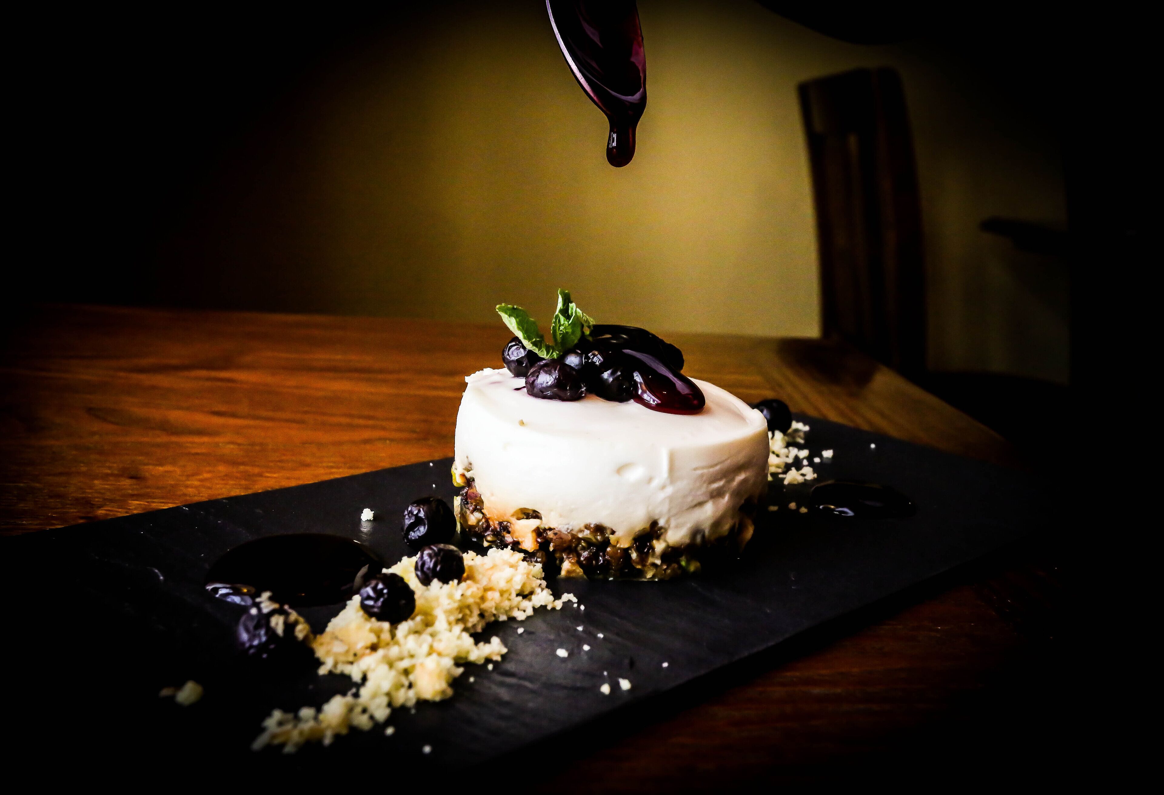 A dessert on a black slate plate with a dark background.