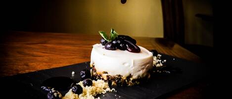 Un postre sobre un plato de pizarra negra con fondo oscuro.