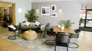 A modern lounge area with a sofa, chairs, a wooden table, and a large mirror. - Crown Hotel (Carlisle)