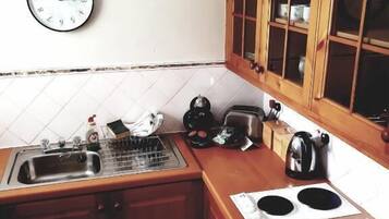 A small kitchen with a sink, stove, and wooden cabinets.