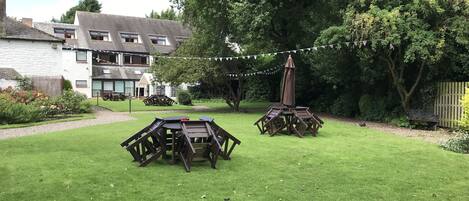 Un espace extérieur verdoyant avec des tables de pique-nique et une pergola.