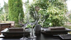A table set with wine glasses, a vase with greenery, and folded napkins. - Crown Hotel (Carlisle)
