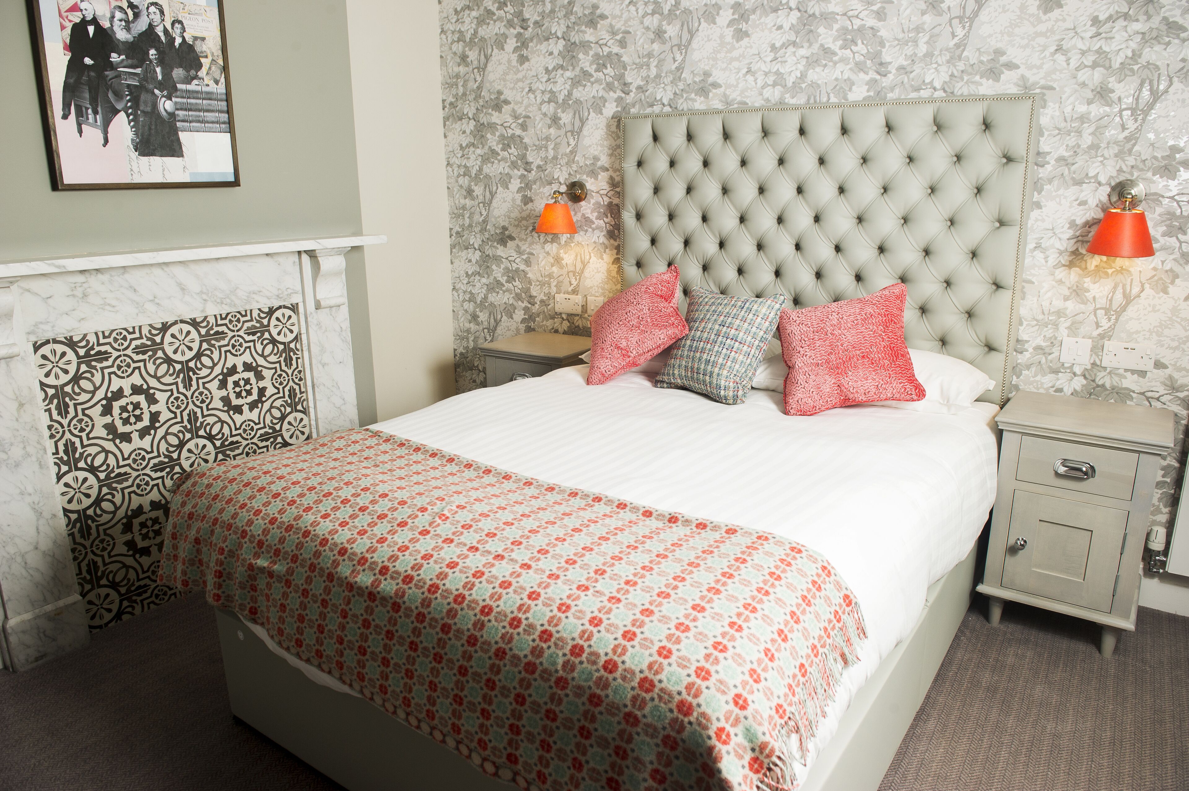 A neatly made bed with a patterned bedspread, a tufted headboard, and two bedside lamps.