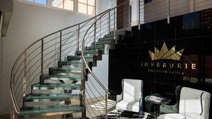 Un intérieur moderne avec un escalier en verre, un lustre et un tapis à motifs zébrés.