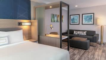 Une chambre d’hôtel avec un lit, un bureau, un canapé et une lampe.