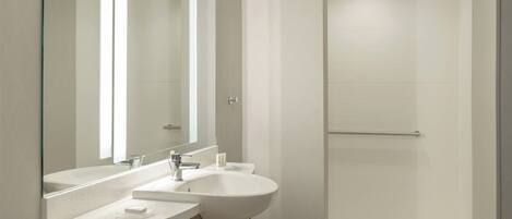 A modern bathroom with two sinks, a large mirror, and a walk-in shower.