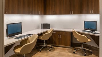 A modern office space with two desks, each with a computer and keyboard, and two beige office chairs.