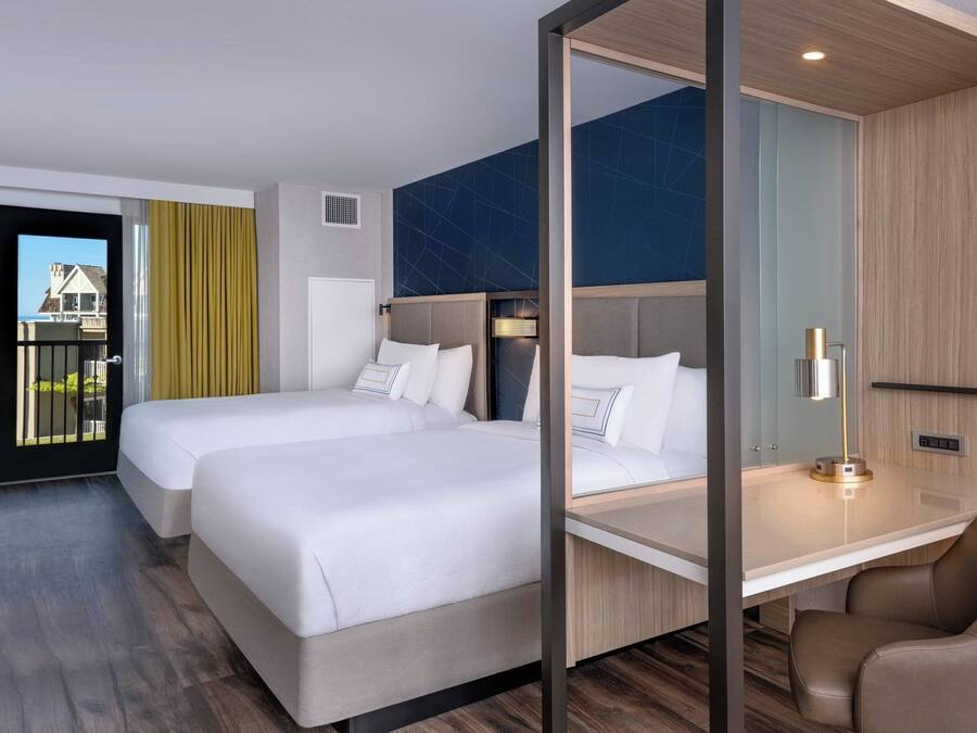 Habitación de hotel con dos camas, un escritorio y una silla.