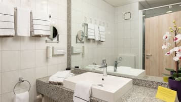 A modern bathroom with two sinks, a large mirror, and a towel rack.
