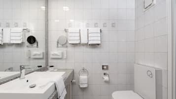 Un baño moderno con un lavamanos amplio, espejo y retrete.