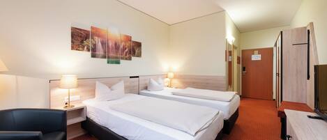 Una camera d'albergo con due letti, una scrivania, una sedia e un'opera d'arte appesa al muro.