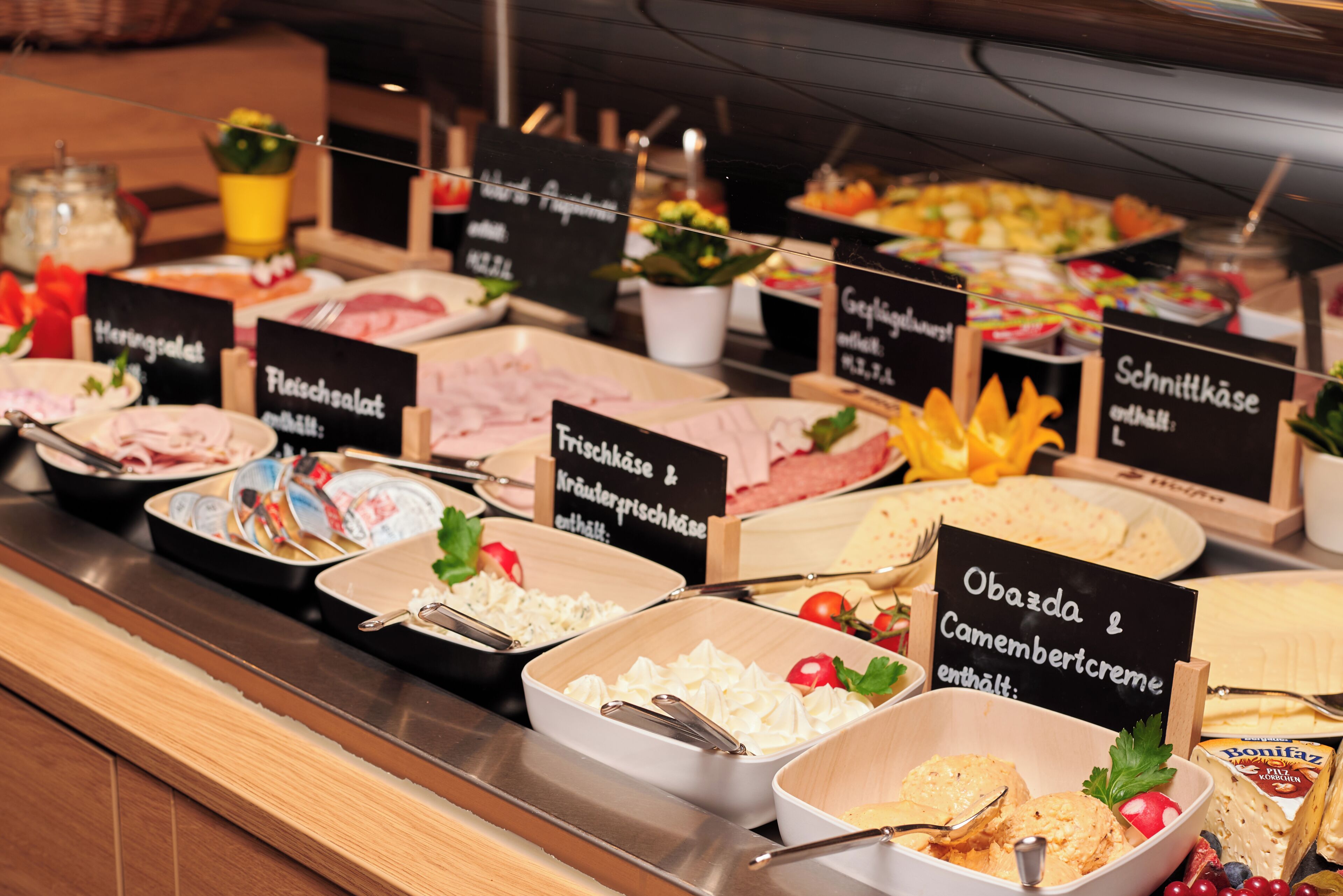 A buffet with various food options and labels in German.