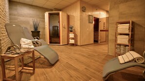 Un cuarto de sauna con pisos de madera, dos sillones reclinables, un estante con toallas y un armario de madera.