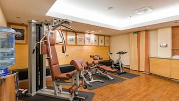 Et fitnessrum med løbebånd, vægtbænke og en vanddispenser.