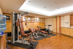 Un gimnasio con máquinas de cardio, bancos de pesas y un dispensador de agua.