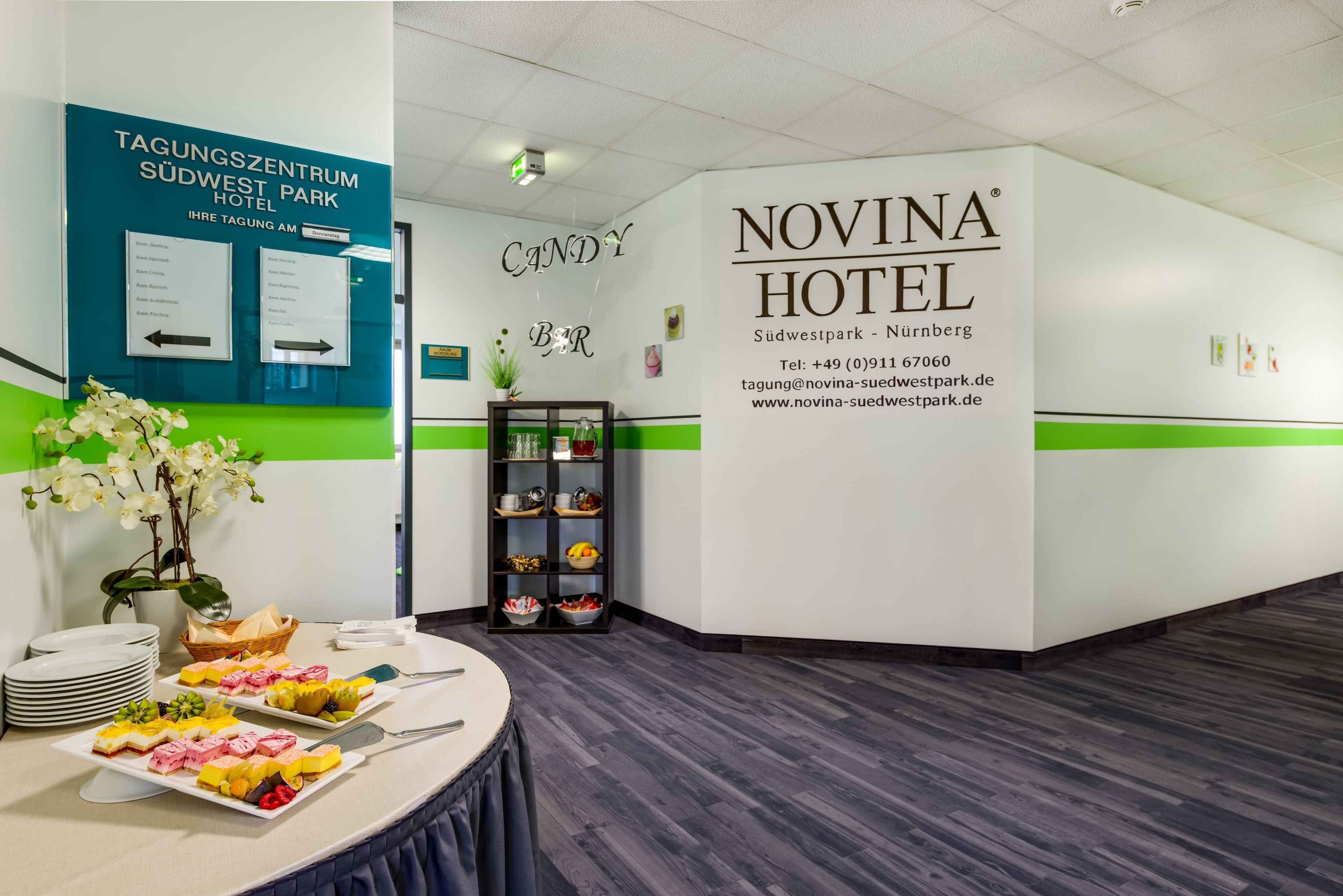 A hotel reception area with a buffet table displaying various desserts and a sign for the Novina Hotel.