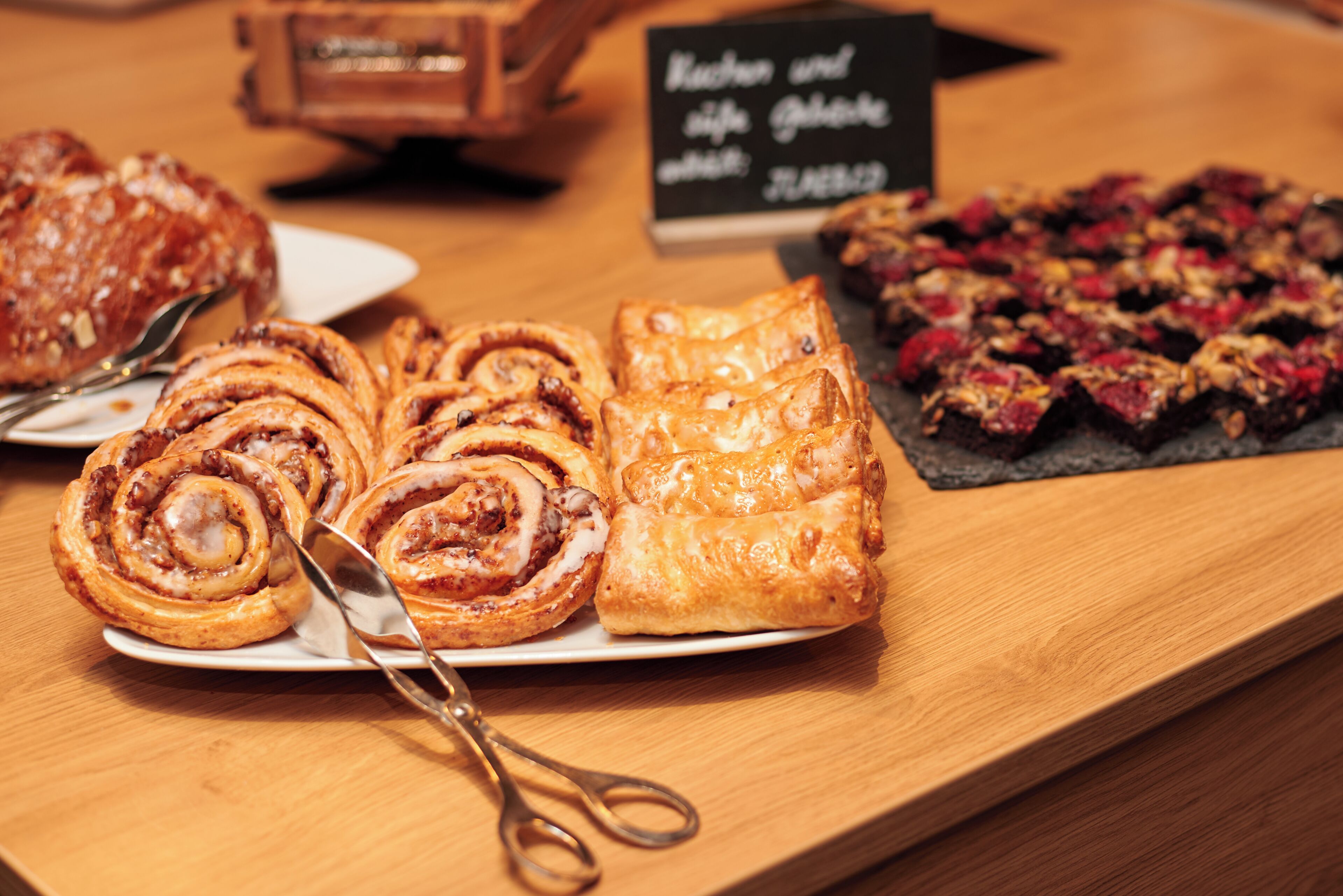 A variety of pastries on a wooden table with a sign in the background.