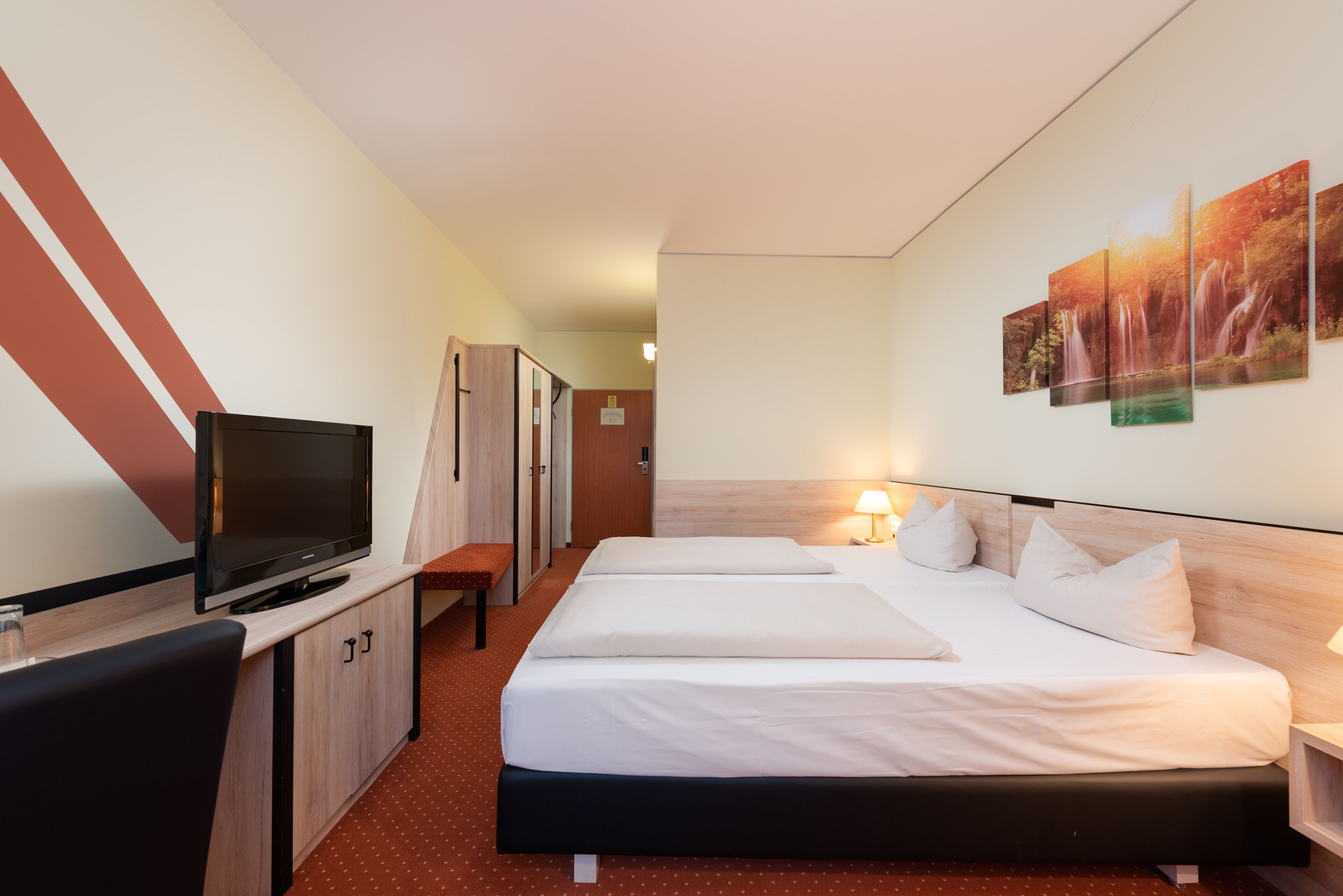 A hotel room with a TV, two beds, a desk, and a cabinet.