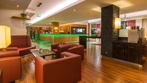 Un vestíbulo moderno con asientos de cuero, un mostrador de recepción e iluminación verde.