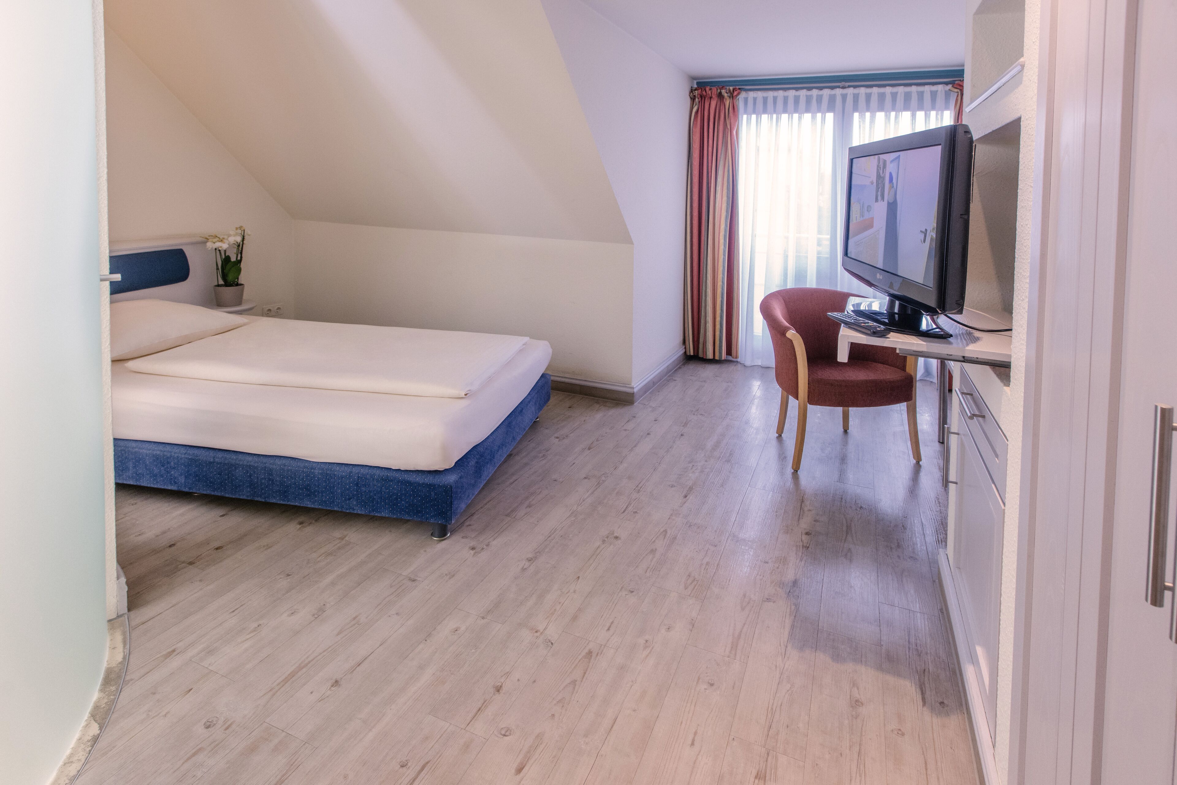 Un dormitorio con una cama, televisión y escritorio.