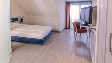 Un dormitorio con una cama, televisión y escritorio.