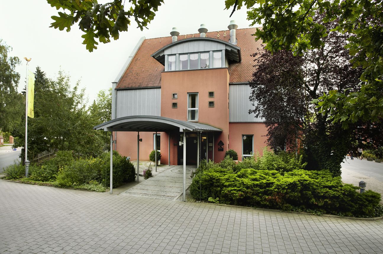 A building with a curved roof, a covered entrance, and a paved driveway.