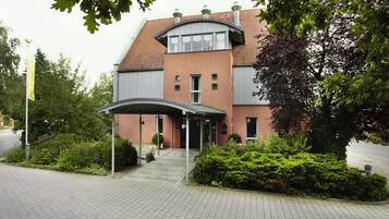 A building with a curved roof, a covered entrance, and a paved driveway.