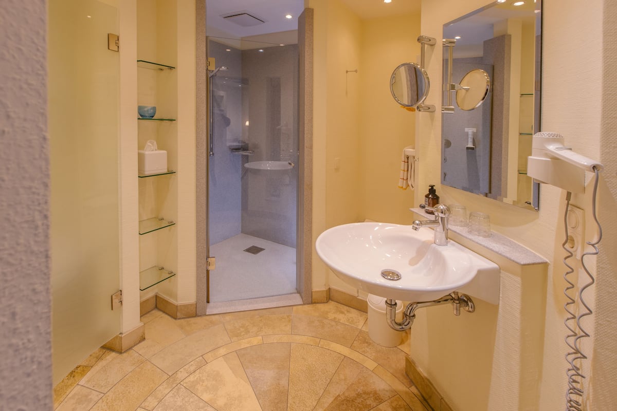 A bathroom with a glass shower enclosure, a sink with a mirror, and a towel rack.