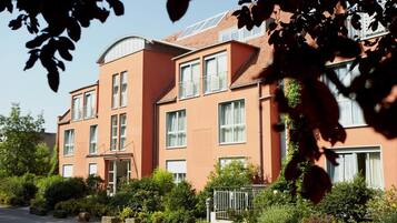 A multi-story building with a curved roof, large windows, and a well-maintained garden.