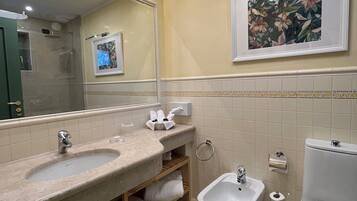 A modern bathroom with a large mirror, a sink, a bidet, and a toilet.