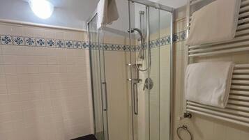 Un baño con ducha envuelta en vidrio, un lavabo e inodoro.