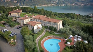 Eine großzügige Villa mit Swimmingpool, umgeben von üppiger Vegetation und Seeblick.