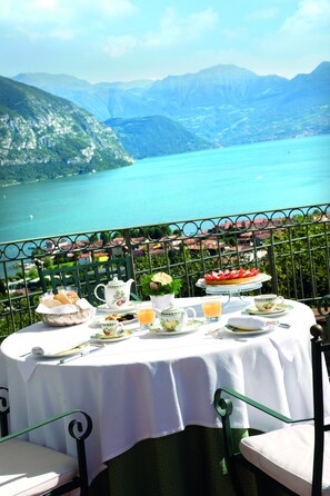 Une table dressée pour le petit-déjeuner, avec une vue pittoresque sur le lac, entourée de chaises en métal.