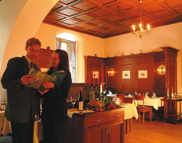 A dining area with wooden paneling, a chandelier, and a table set for a meal.