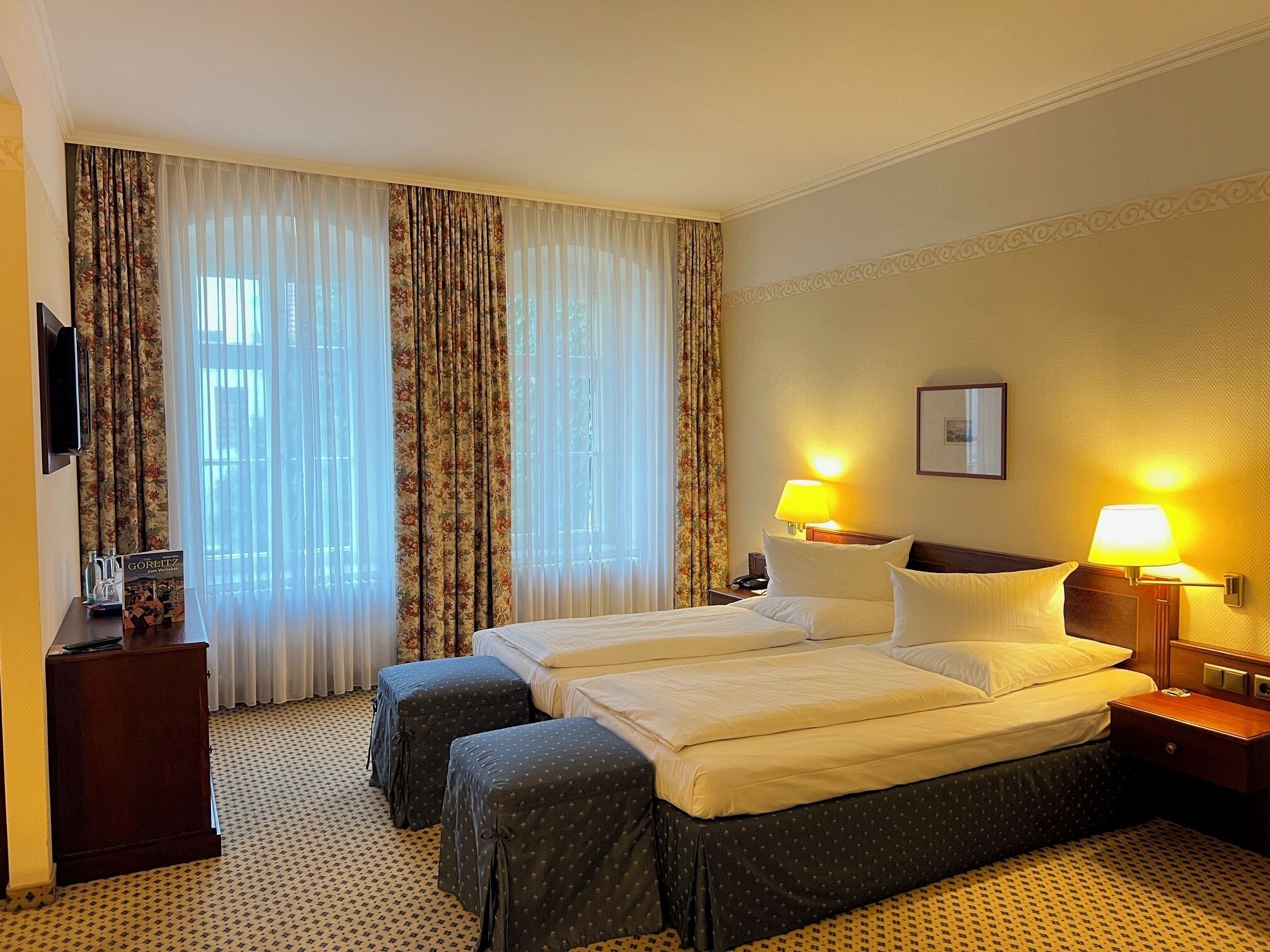 Una habitación de hotel con dos camas, un televisor, un escritorio y una lámpara.