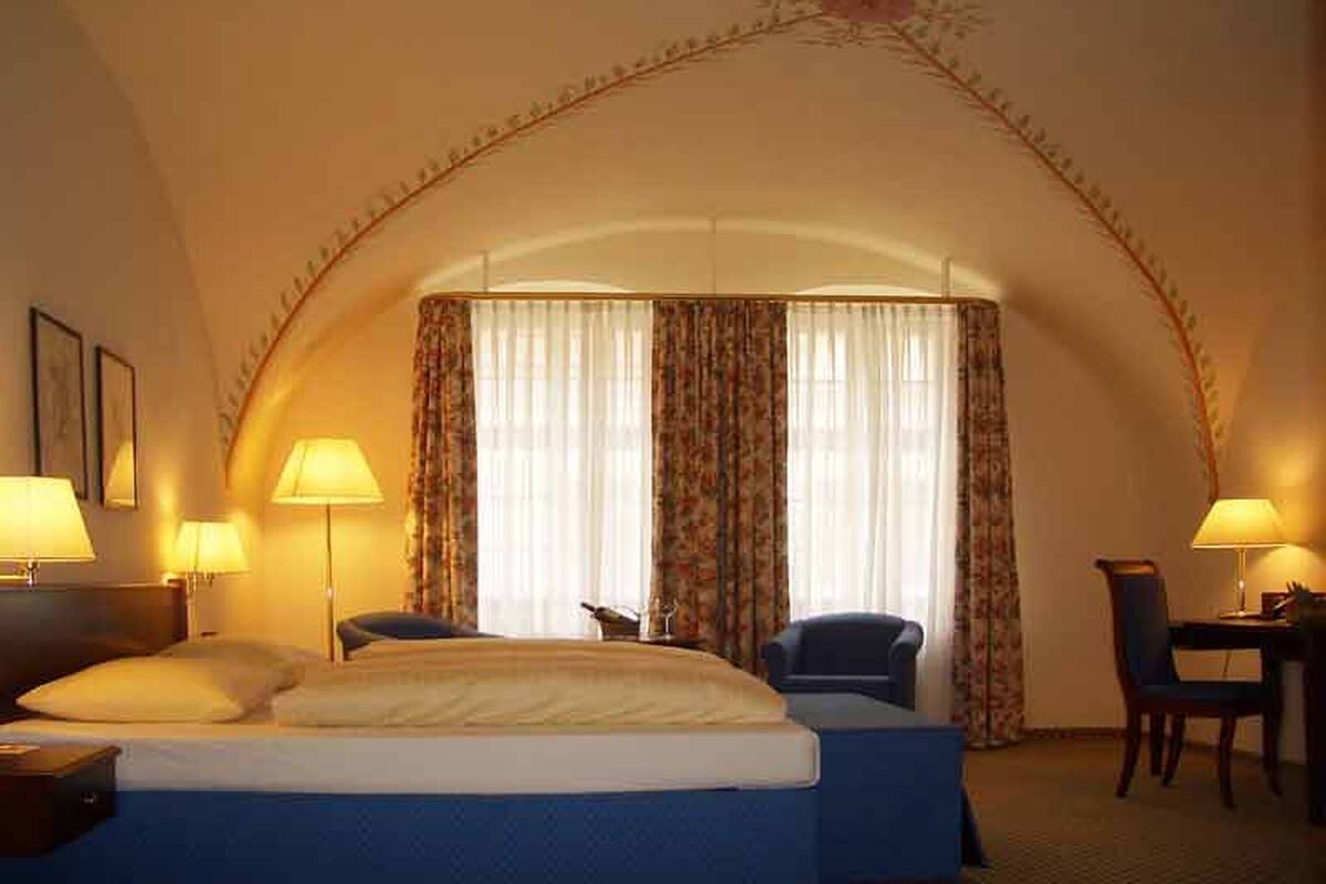 Una habitación de hotel con una cama, dos sillones, un escritorio y dos lámparas.
