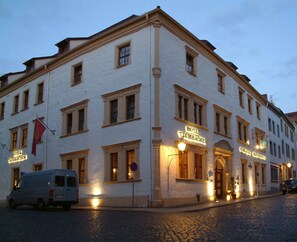 Un edificio histórico con un cartel que dice "Hotel Tuchmacher" y una furgoneta estacionada al frente.
