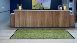 Un comptoir d’accueil d’hôtel au design moderne, une grande peinture abstraite accrochée au-dessus, et un luminaire au plafond.