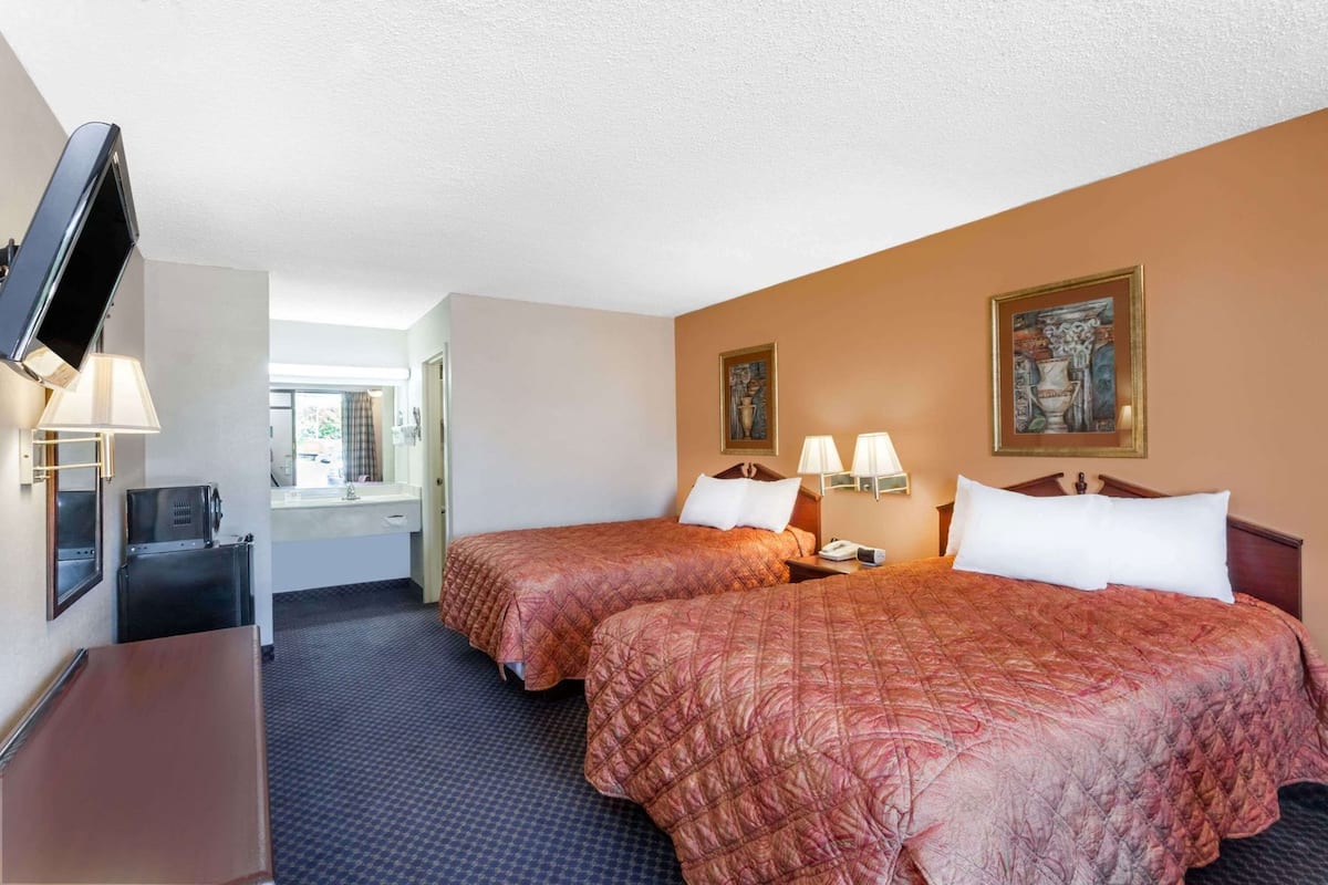 Une chambre d’hôtel avec deux lits, un bureau, une télévision et une fenêtre.