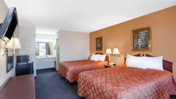 Quarto de hotel com duas camas, televisão, escrivaninha e janela.